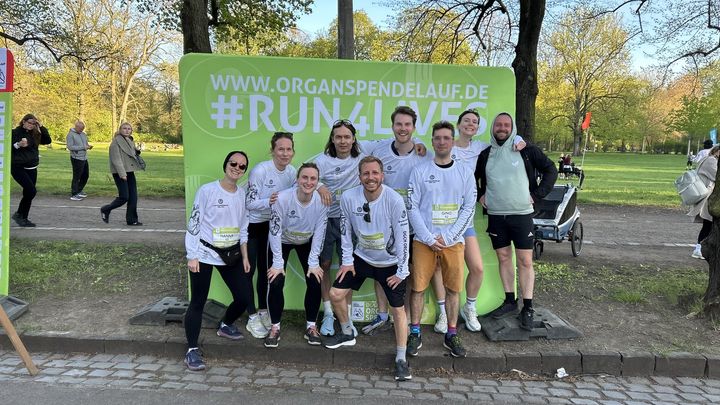 Das Evergreen-Laufteam in Startnummern vor der Fotowand des Organspendelaufs.