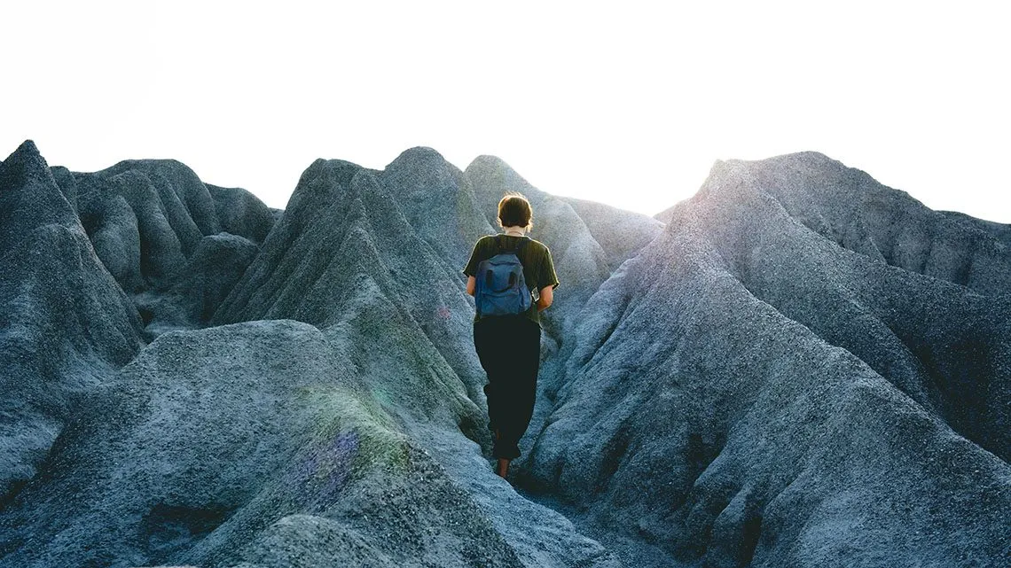 Person wandert allein durch eine graue Felslandschaft